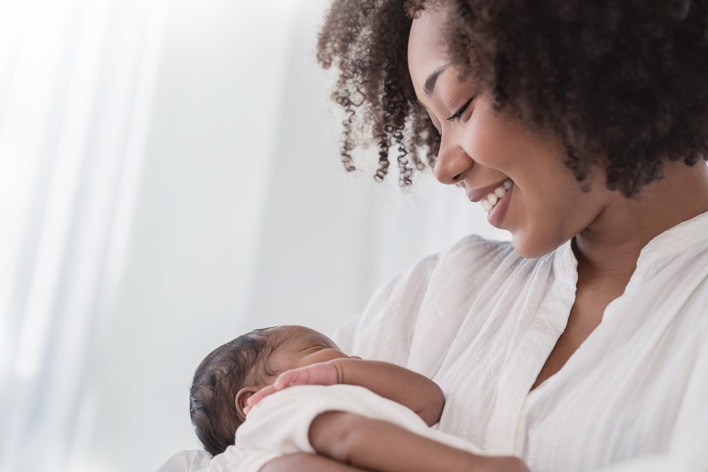 Close up portrait of beautiful young African American mother holding her baby