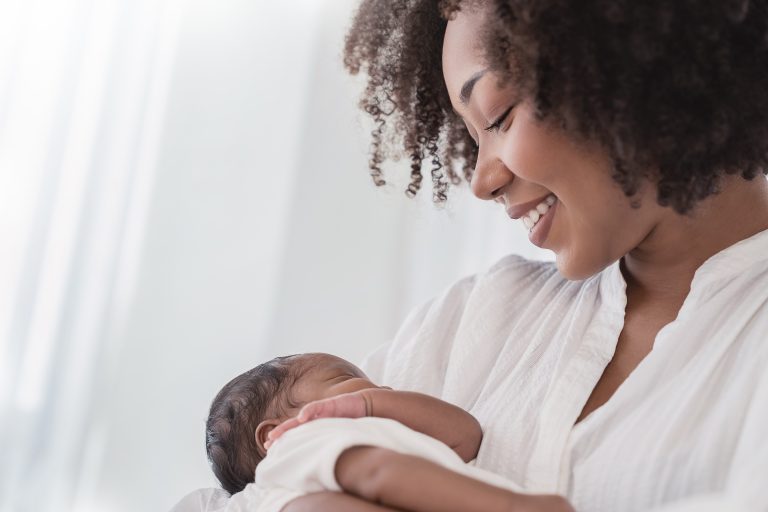 Close up portrait of beautiful young African American mother holding her baby