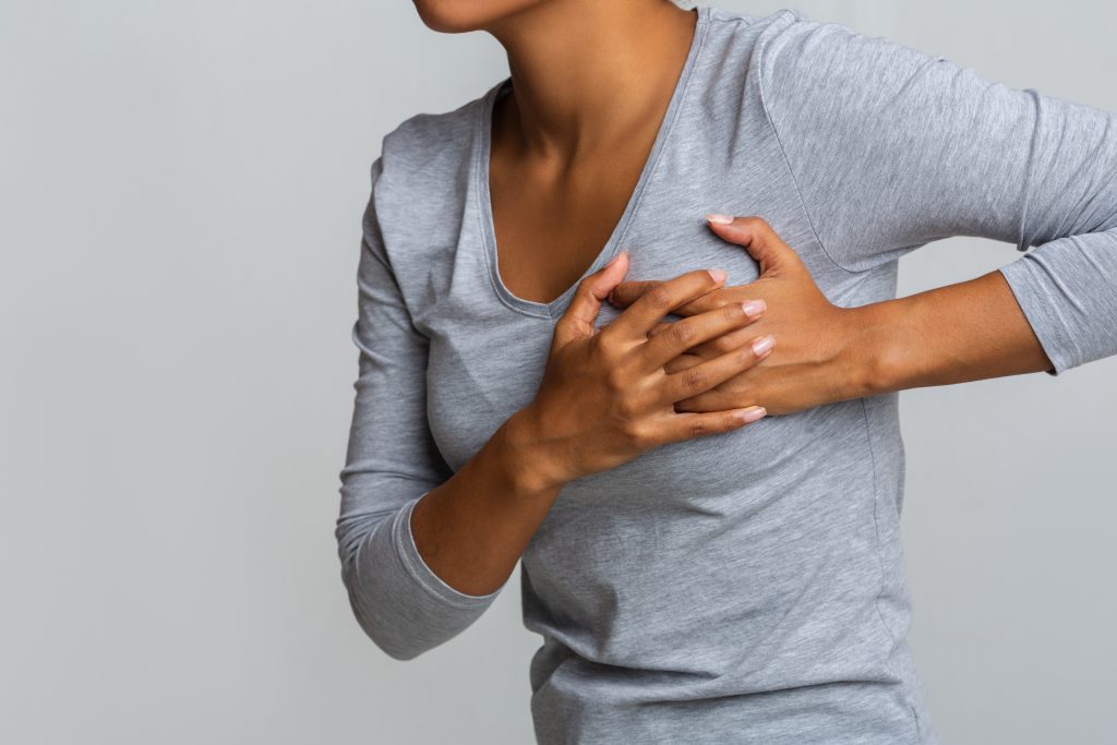 Young woman feels breast pain, touching her chest