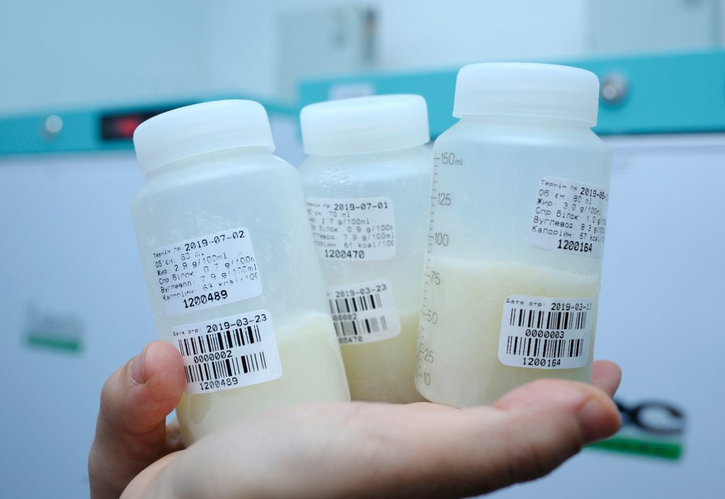 At the Human Milk Bank laboratory. Lab assistant hands holding three bottles of milk